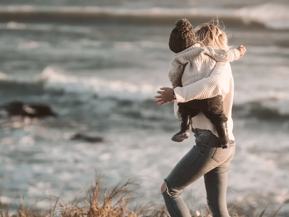 A mother carrying her child on the Cape Town coast