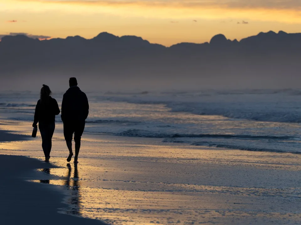 A couple walking along a Cape Town beach at sunrise